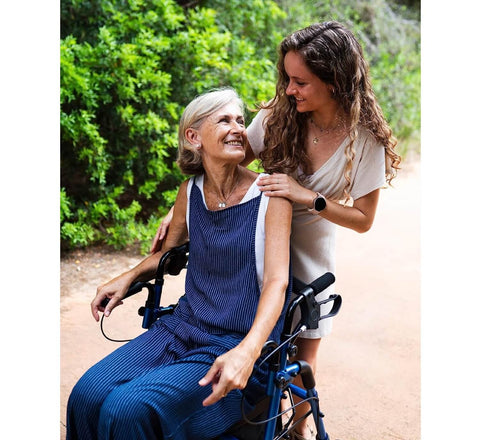 Woman in a wheelchair with another woman outdoors