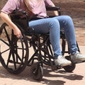 Person in a wheelchair on a paved surface with a blurred background