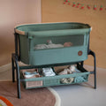 Green baby crib with a baby inside in a room setting.