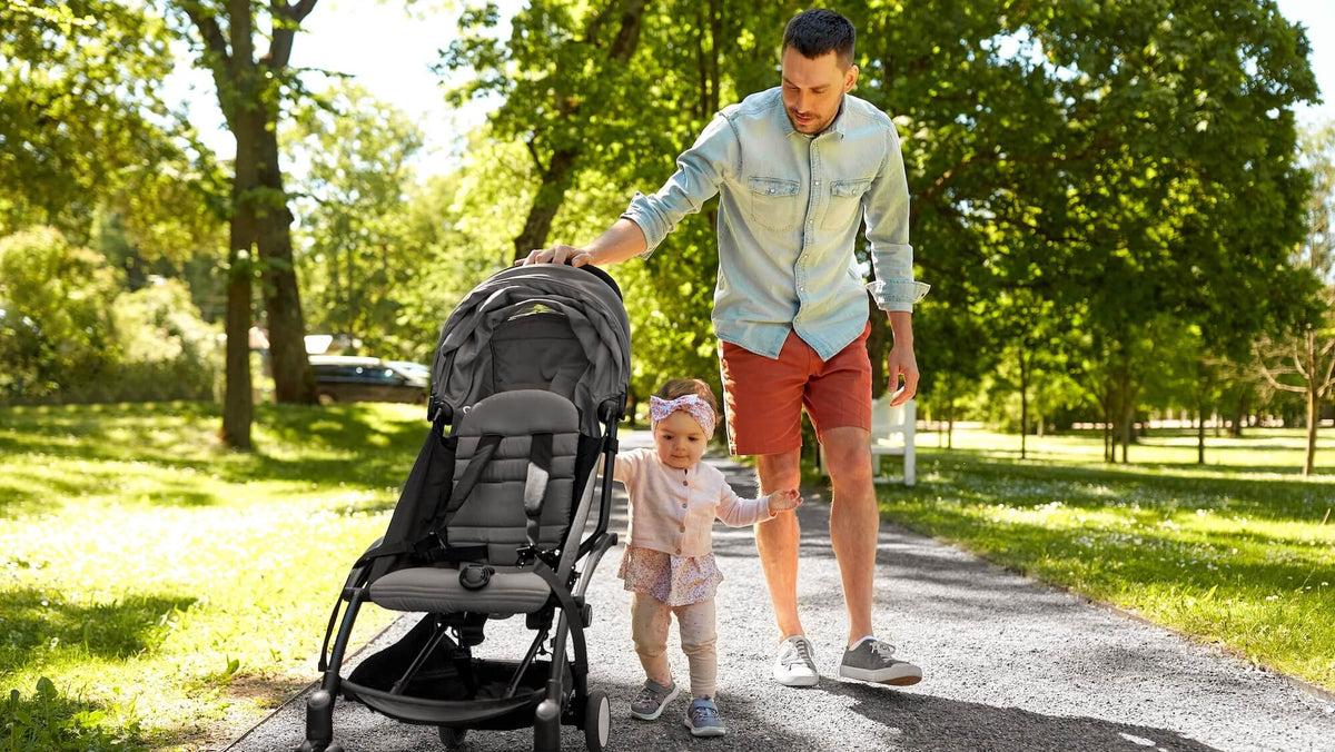Man and child walking with a stroller in a park