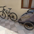 Bicycle with a child trailer attached on a checkered pavement.