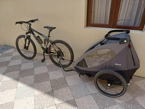 Bicycle with a child trailer attached on a checkered pavement.